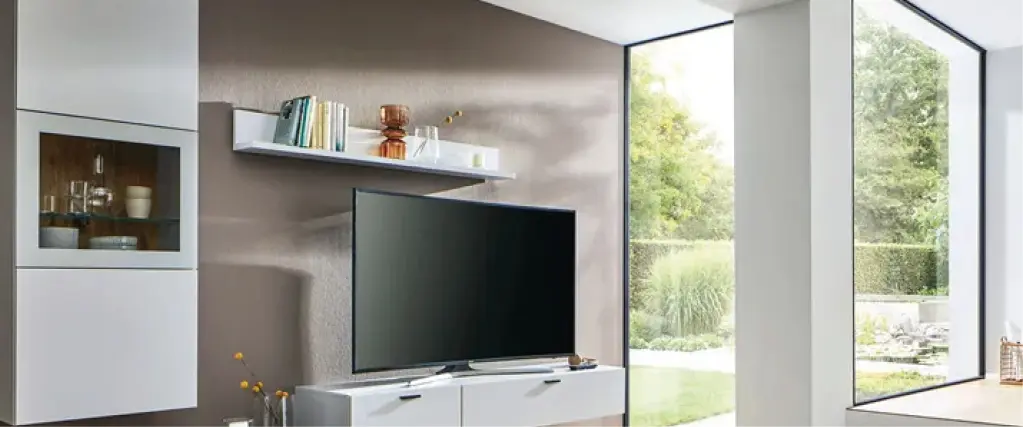 Hochwertiges Sideboard aus Massivholz mit integrierter Glasvitrine und dekorativen Vasen. Daneben ein Bücherregal aus Holz. Moderne Wohnmöbel in natürlicher Holzoptik für stilvolle und langlebige Wohnzimmer Einrichtung.